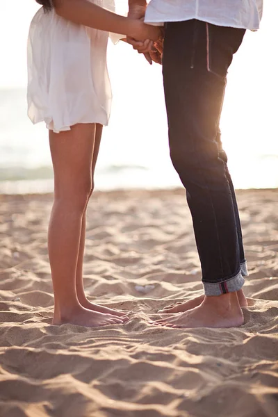 As pernas da mulher e do homem em pé na areia Imagem De Stock