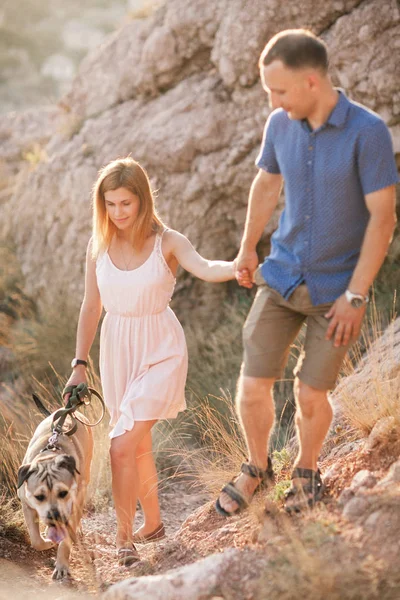 Couple of guys playing with their dog on the mountain near ocean