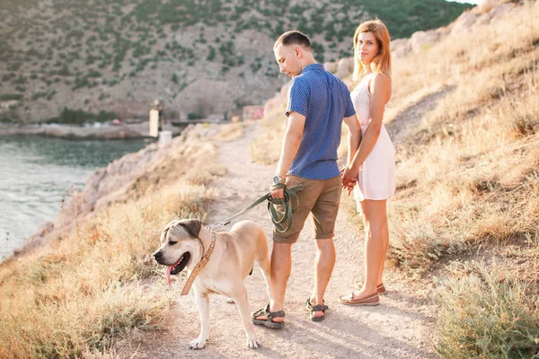 Couple of guys playing with their dog on the mountain near ocean — Stock Photo, Image