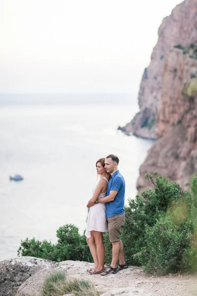 Casal de caras brincando com seu cão na montanha perto do oceano — Fotografia de Stock