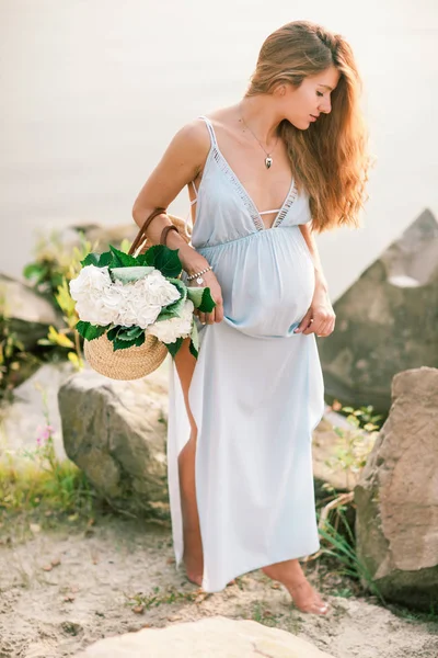 Yakınındaki bir yazlık elbise çiçeklerle gölün kıyısında yürüyüş uzun saçlı güzel hamile kız — Stok fotoğraf