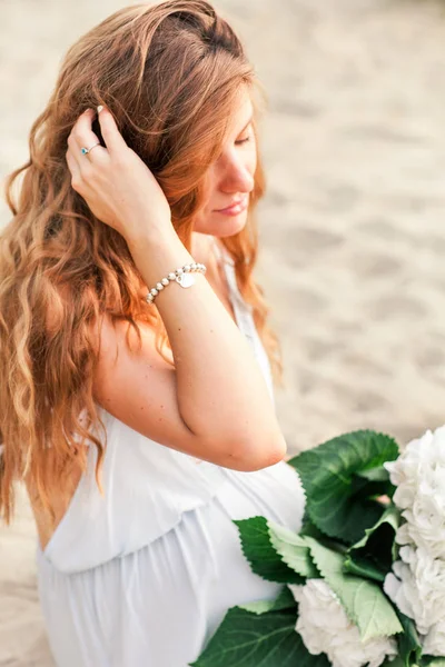 Bela menina grávida com cabelos longos andando perto da costa de um lago com flores em um vestido de verão — Fotografia de Stock