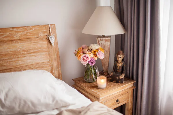 Drewniane łóżko z pościelą. Stolik przy łóżku z — Zdjęcie stockowe