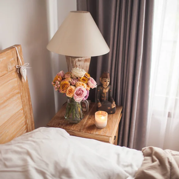 Cama de madeira com lençóis brancos. Uma mesa de cabeceira ao lado da cama com um — Fotografia de Stock