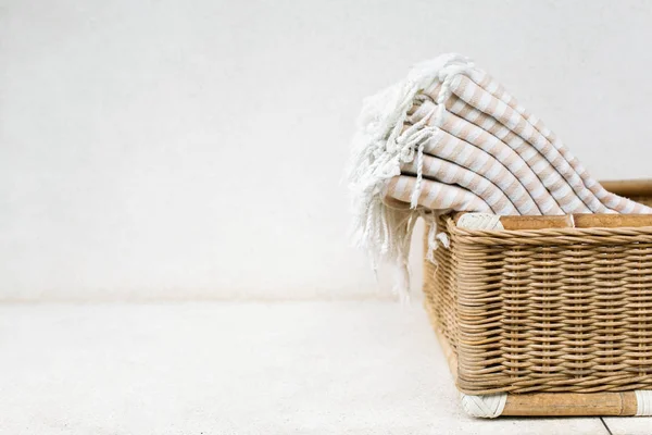 Toalhas de algodão listrado branco na cesta de vime contra a parede branca . — Fotografia de Stock