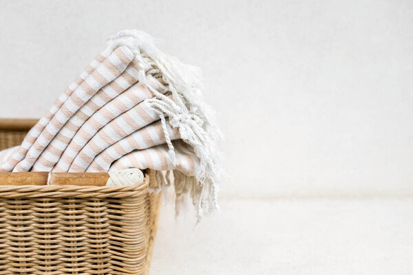 White stripe cotton towels in whicker basket against white wall.