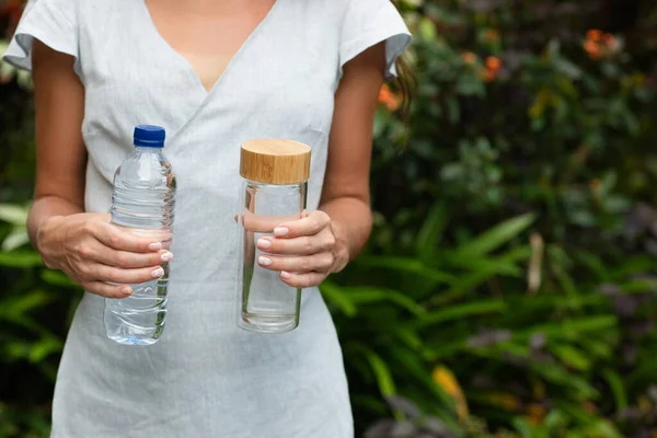 Botella de plástico y vidrio en manos de mujer, concepto de elección . — Foto de Stock