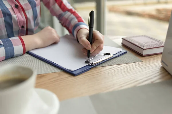Die Hand des Mädchens schreibt mit schwarzem Stift auf ein weißes Blatt Papier — Stockfoto