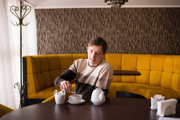 Молодой человек кладет сахар в чай — стоковое фото