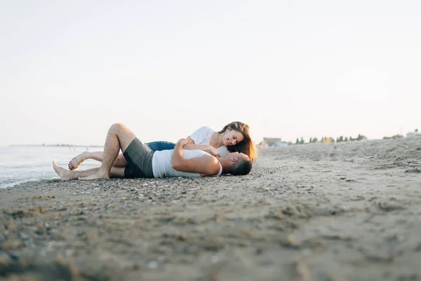 Den älskande par med ett leende ligger på havsstranden — Stockfoto