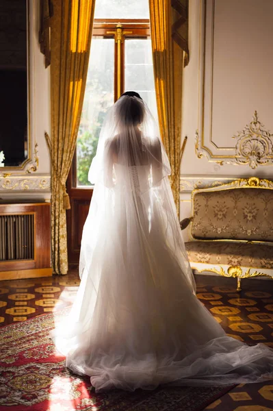 La novia está de pie frente a la ventana sosteniendo un ramo — Foto de Stock