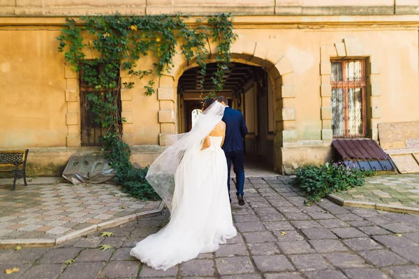 Наречений і наречена йдуть під арку, тримаючись за руки — стокове фото