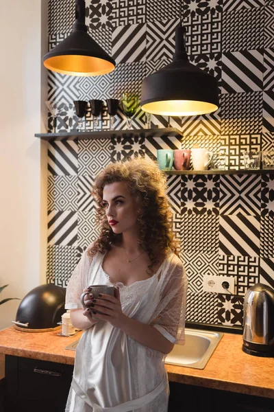 Девушка с вьющимися волосами стоит на кухне — стоковое фото