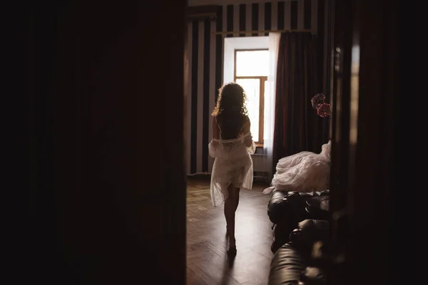 Silhouet van een meisje met een mooie afbeelding die rond de kamer naar het venster loopt — Stockfoto