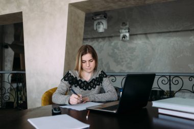 Öğrenci masada oturan ve bir şey bir kağıt parçası üzerinde yazılı