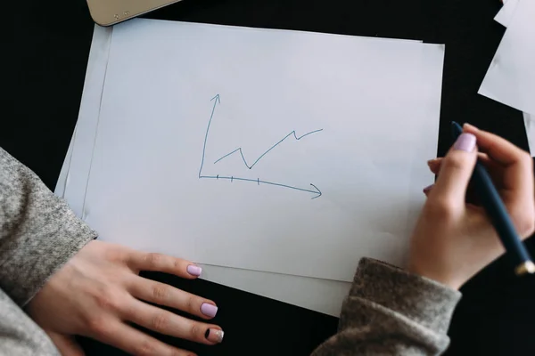 Sobre el papel la gráfica del crecimiento cerca del papel por dos manos — Foto de Stock