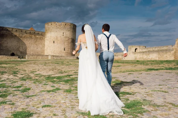 Наречений тримає наречену руками і вони ходять навколо фортеці — стокове фото