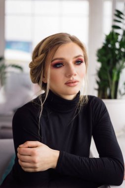 Genç bir kadın, dalgın bir bakışla bir kafede masada oturur.