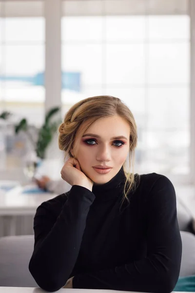 An interesting young woman sits in a cafe by the window, — Stock Photo, Image