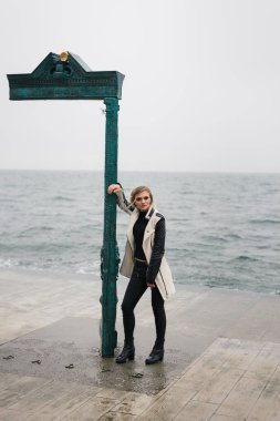 Birisi denizin kenarında kaldırımda bekliyor dalgın güzel genç kız,.