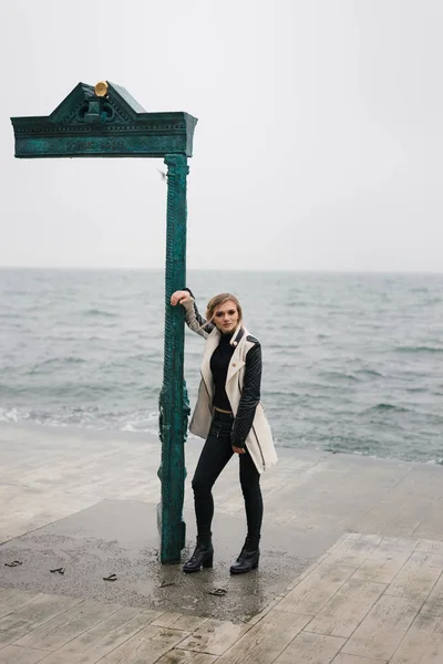 Chica hermosa y pensativa, que está esperando a alguien en el pavimento junto al mar . — Foto de Stock