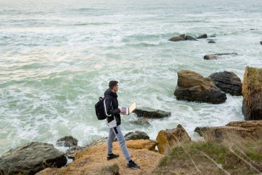bir adam bir dizüstü bilgisayar tutarak ve mesafe içine bakıyor