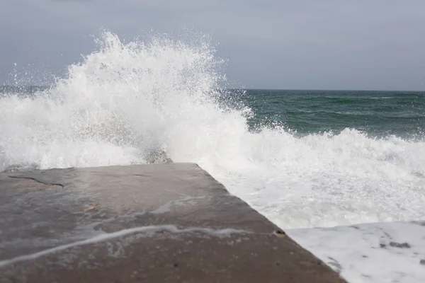 暴风雨时海面上的巨浪覆盖着一块石头码头 — 图库照片