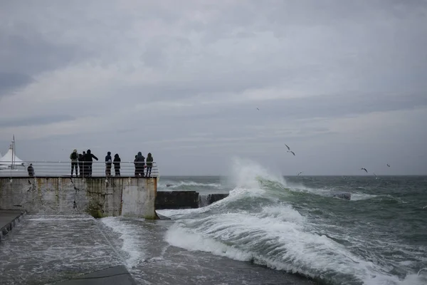 A crowd of people is standing on a pier during a storm — Stock Photo, Image