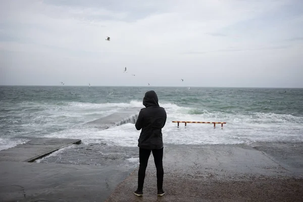 O cara está de pé no cais e admirando o mar — Fotografia de Stock