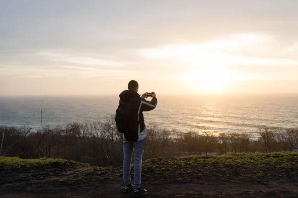 The guy takes a picture of the sunrise on the phone — Stock Photo, Image