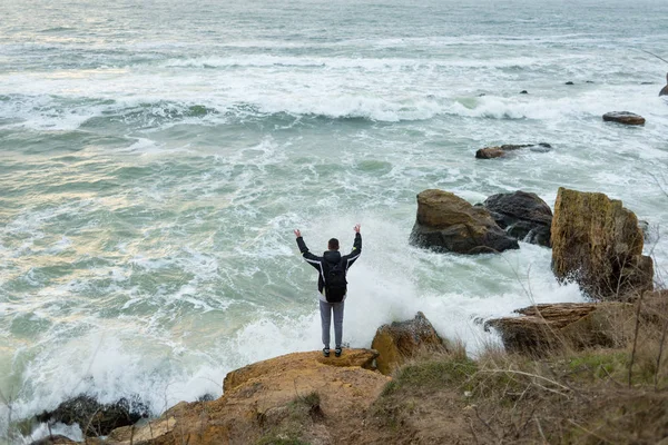O cara está de pé sobre uma rocha e levantou as mãos — Fotografia de Stock