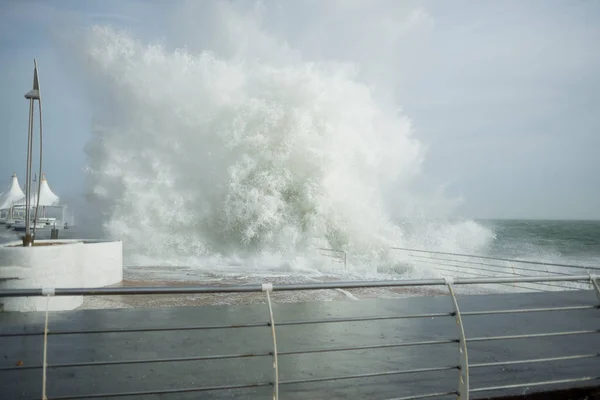 A onda do mar bate contra o cais a partir dele voa um monte de espirrar ao redor — Fotografia de Stock