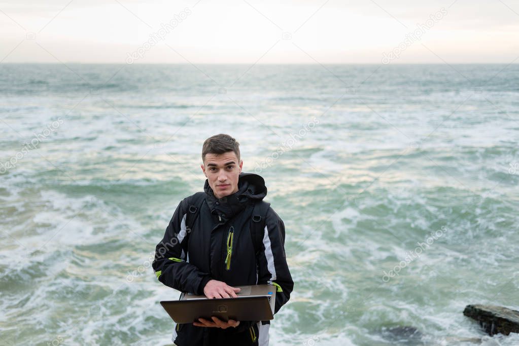guy standing with laptop and looking directly at camera