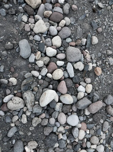異なるサイズと色の石が地面にあり、背景 — ストック写真
