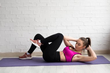 Spor salonu basında, kız paspasla antrenman yapıyor.