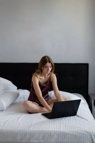 Hermosa joven freelancer utilizando un ordenador portátil trabaja en casa a través de Internet . —  Fotos de Stock