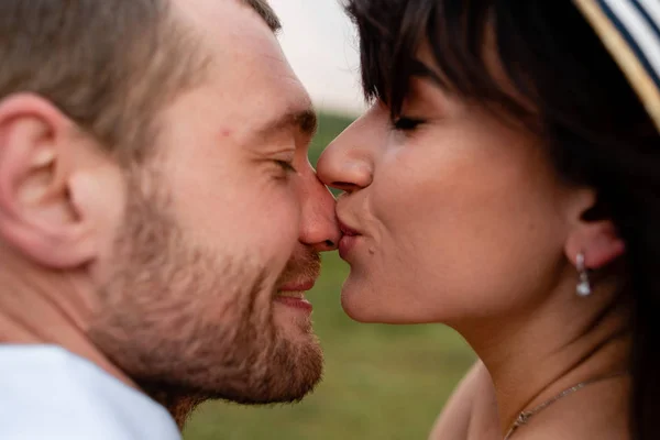 Дівчина цілує хлопця в носі, закохана пара в природі — стокове фото