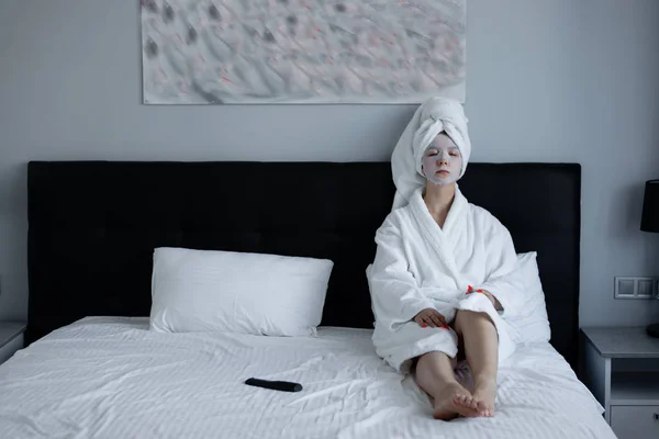 Mujer hizo spa antioxidante mascarilla hidratante para la piel de combinación. la chica se sienta en el dormitorio en la cama y se relaja . — Foto de Stock