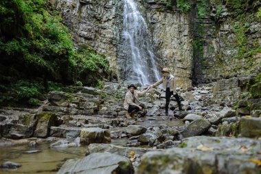 Genç bir çift şelalede el ele tutuşuyor.