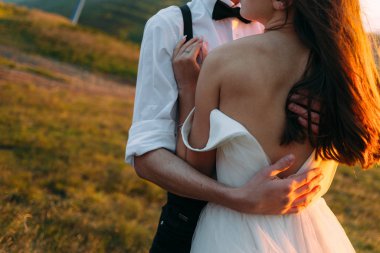Damat geline sarıldı, arkası açık giyindi, arkadan görüldü.