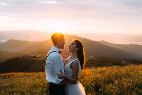 Een man en een vrouw in een witte jurk in de zon, bergen en heuvels op de achtergrond — Stockfoto