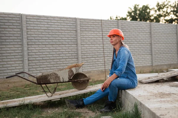 İnşaat üniformalı güzel bir kadın oturur ve önüne bakar.