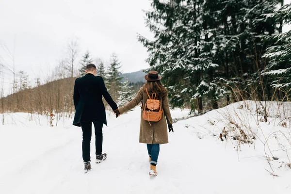 Una pareja enamorada camina en la nieve, una vista desde atrás — Foto de Stock
