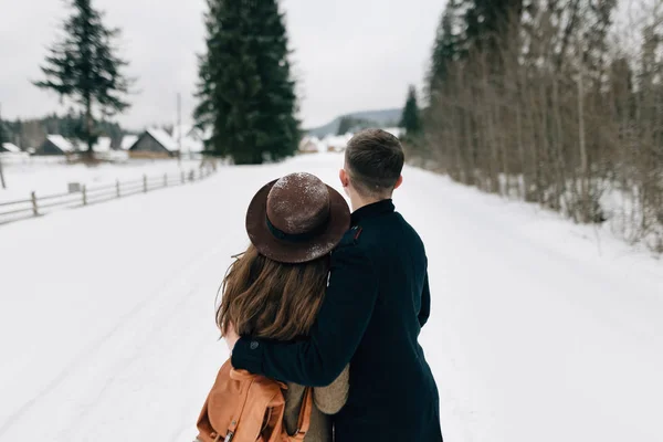 Пара дивиться на село в снігу, вид ззаду — стокове фото