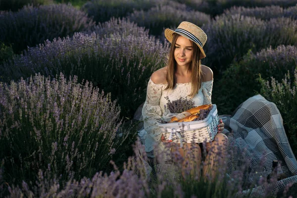 A girl with a basket sits in a lavender field — 图库照片