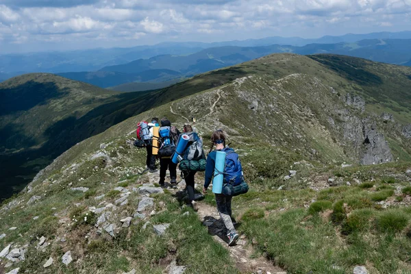 Egy csoport turista sétál végig az ösvényen a hegy tetején. — Stock Fotó
