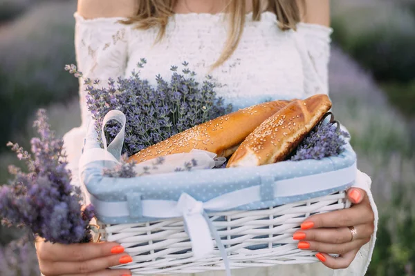 Una mujer sostiene una cesta de pan y lavanda — Foto de Stock