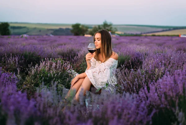 一个女孩在薰衣草地里喝着一杯葡萄酒 — 图库照片