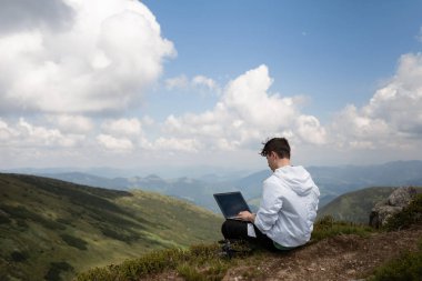Tepenin üstünde bilgisayarı olan bir adam.