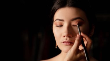 The face of the brunette, who is applied shades of golden color close-up, the work of a make-up artist